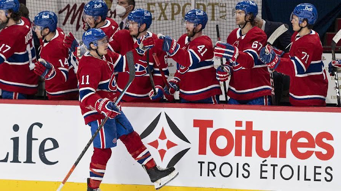 Joueurs de hockey des Canadiens de Montréal (NHL) devant une bande avec annonce de Toitures Trois Étoiles